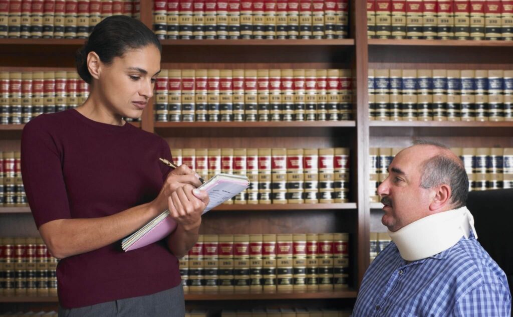personal injury attorney taking notes with injured client wearing neck brace - Decatur, IL
