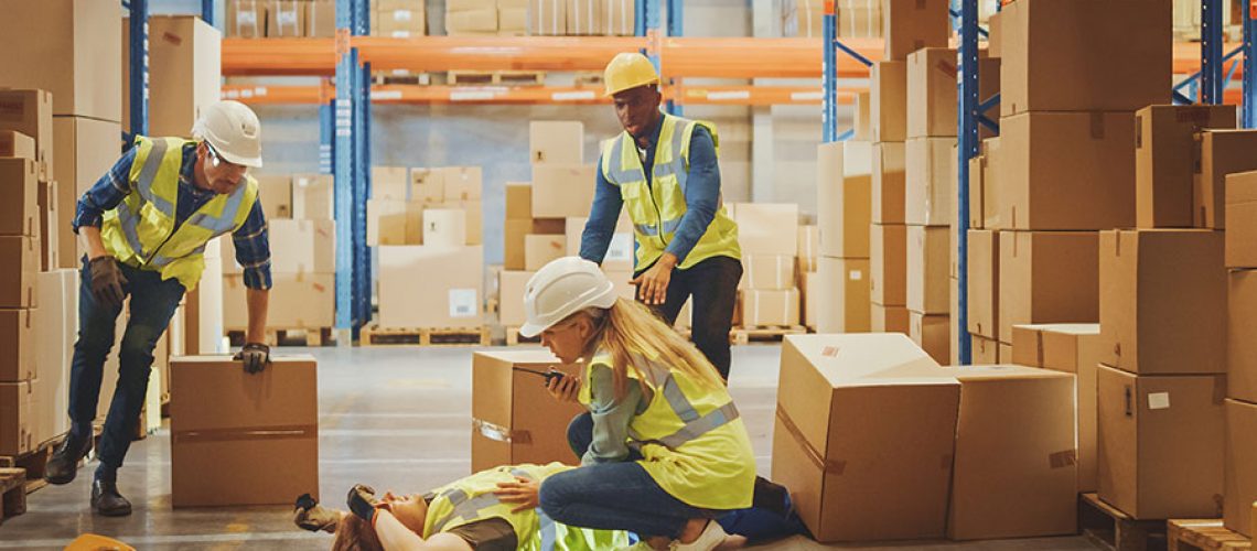 A warehouse worker has a work-related accident and is lying on the ground with possible injuries. Coworkers call for help and medical assistance in Springfield, IL.